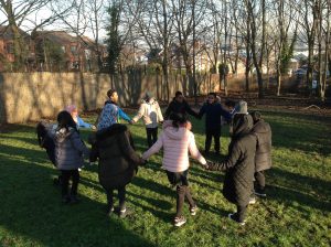 A group of children stand in a circle in a school playground