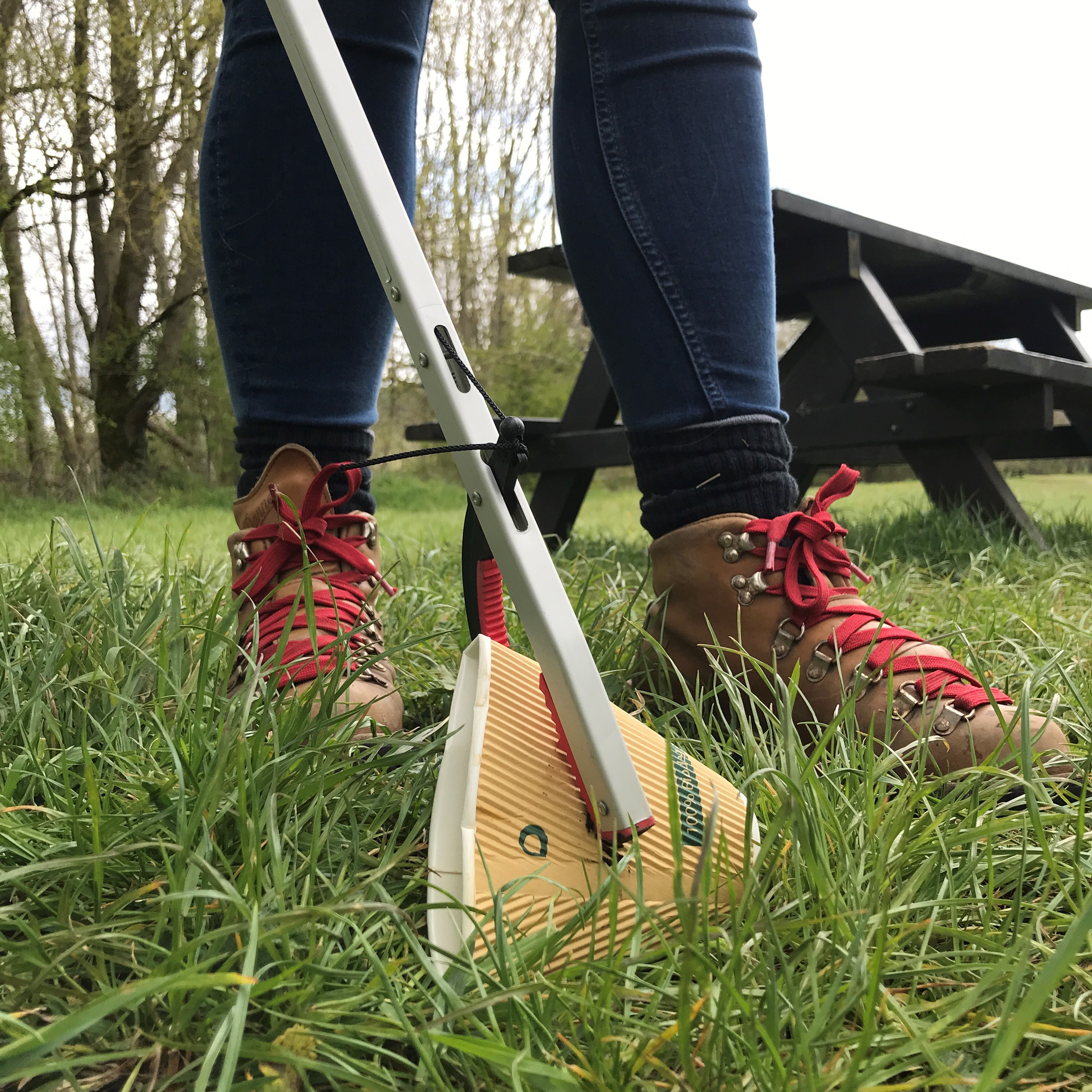 A close up shot of a litter picker being used to pick up a coffee cup