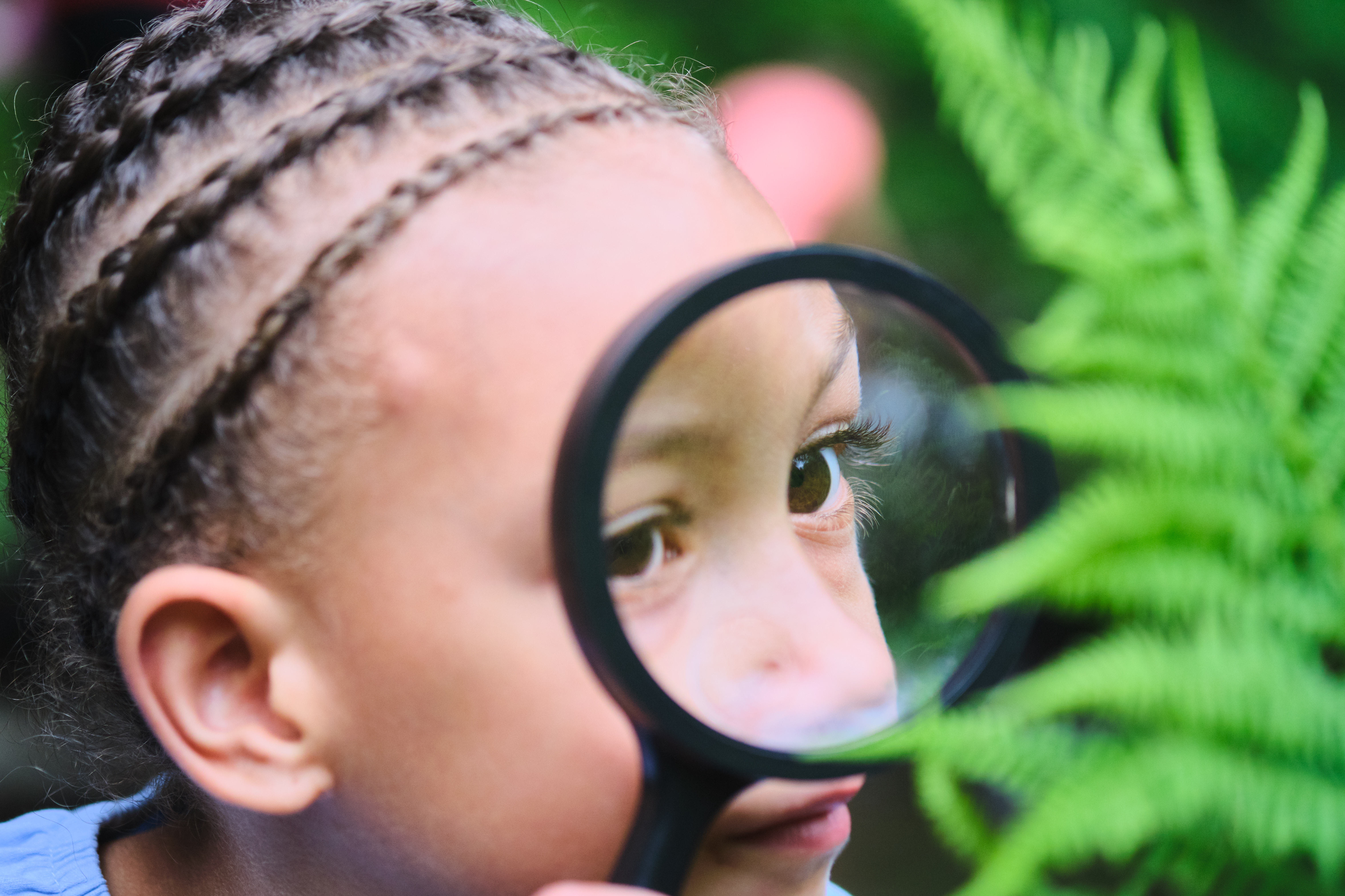 A young child looks through a magnifying glass