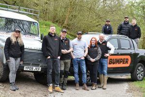 A group of people in Bumper branded clothing stand in front of a National Park truck with trees in the background