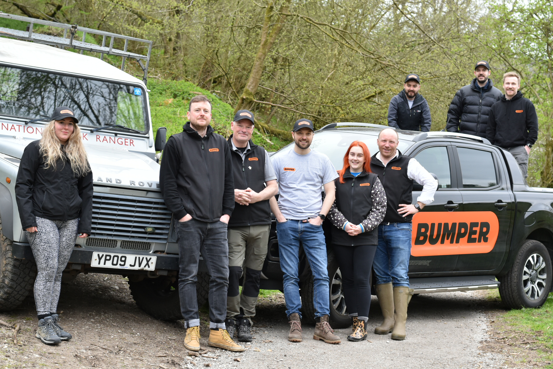 A group of people in Bumper branded clothing stand in front of a National Park truck with trees in the background
