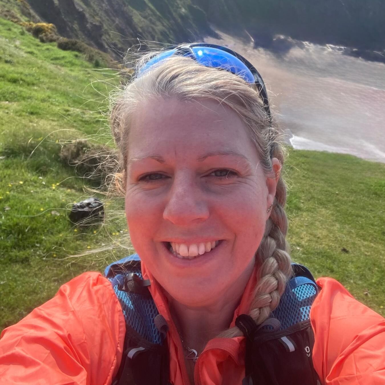 A woman in an orange jacket smiles at the camera.