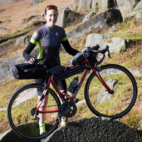 Lorna Fisher poses with her read mountain bike loaded with kit for her epic cycle journey