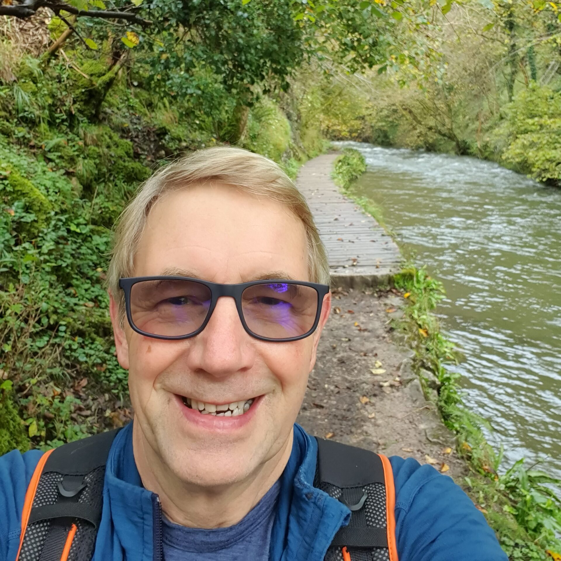 A man wearing sunglasses stands by a river